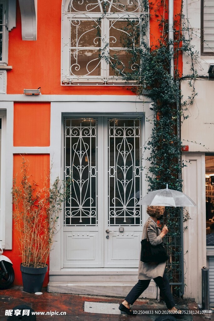 橙墙白门街道撑伞行人