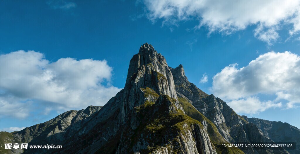 巍峨山峰耸立于蓝天白云间