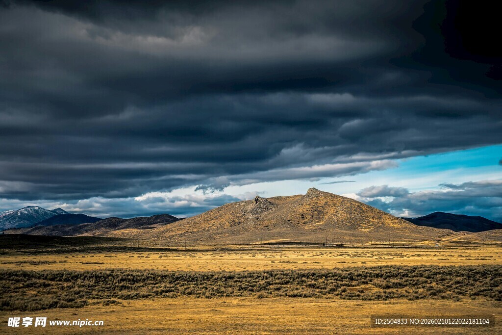 旷野乌云下的孤耸山丘