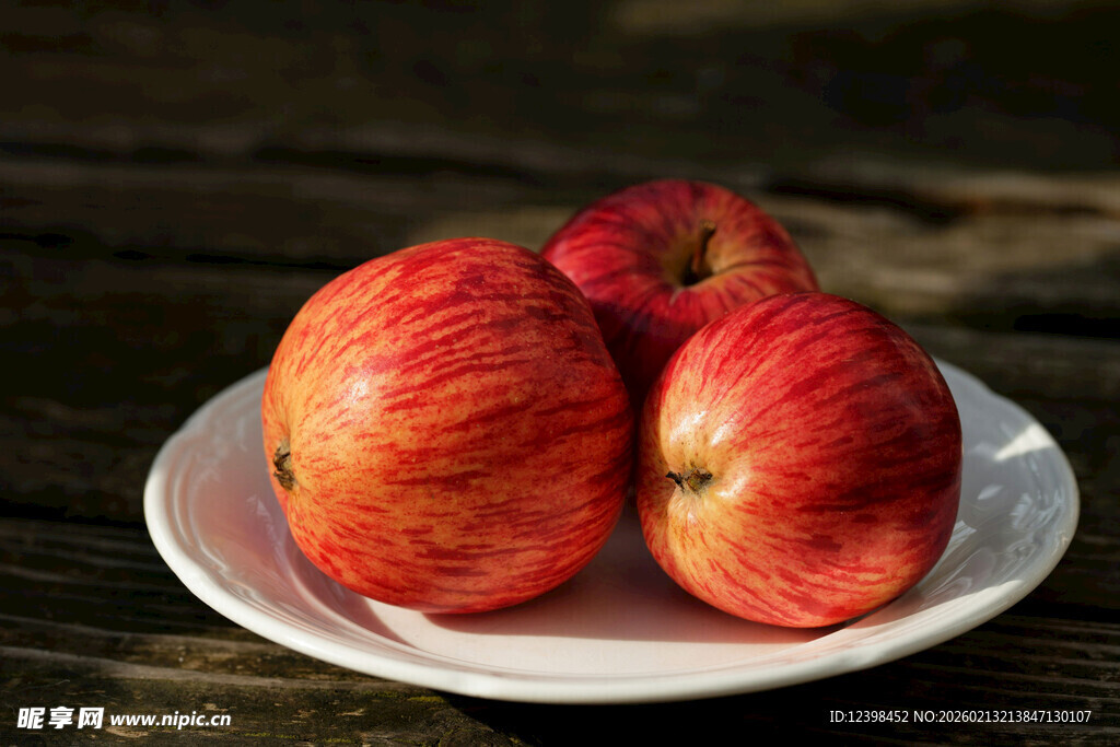木桌上白盘里的红苹果