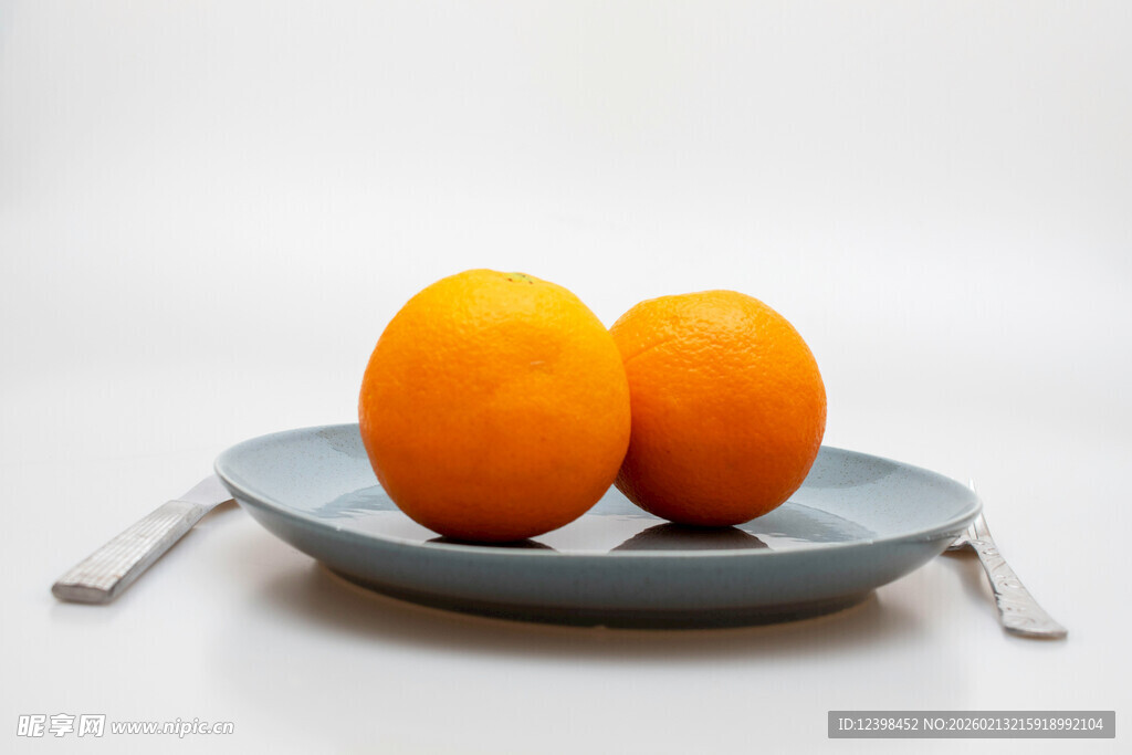 灰盘上的两颗新鲜橙子