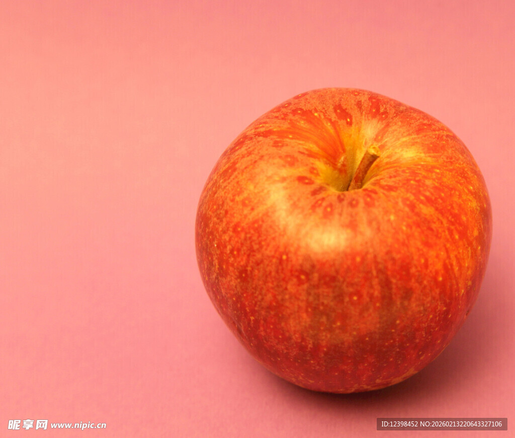 粉红背景上的鲜亮红苹果
