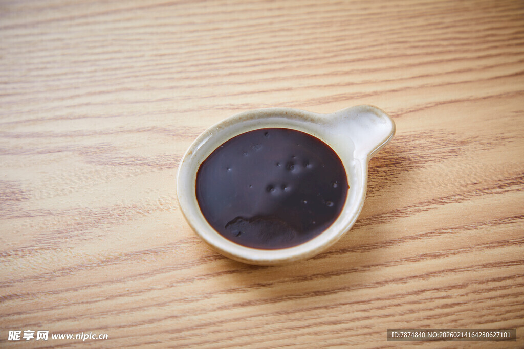 木质桌上的深色酱汁小碗