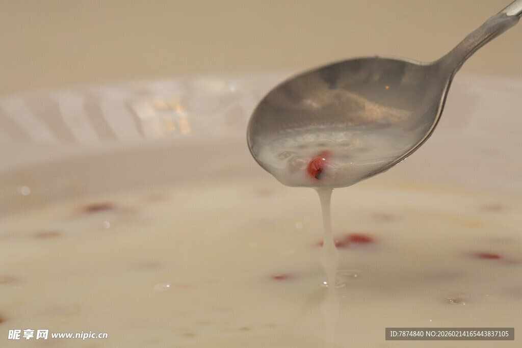 勺子舀起带红粒的白色液体
