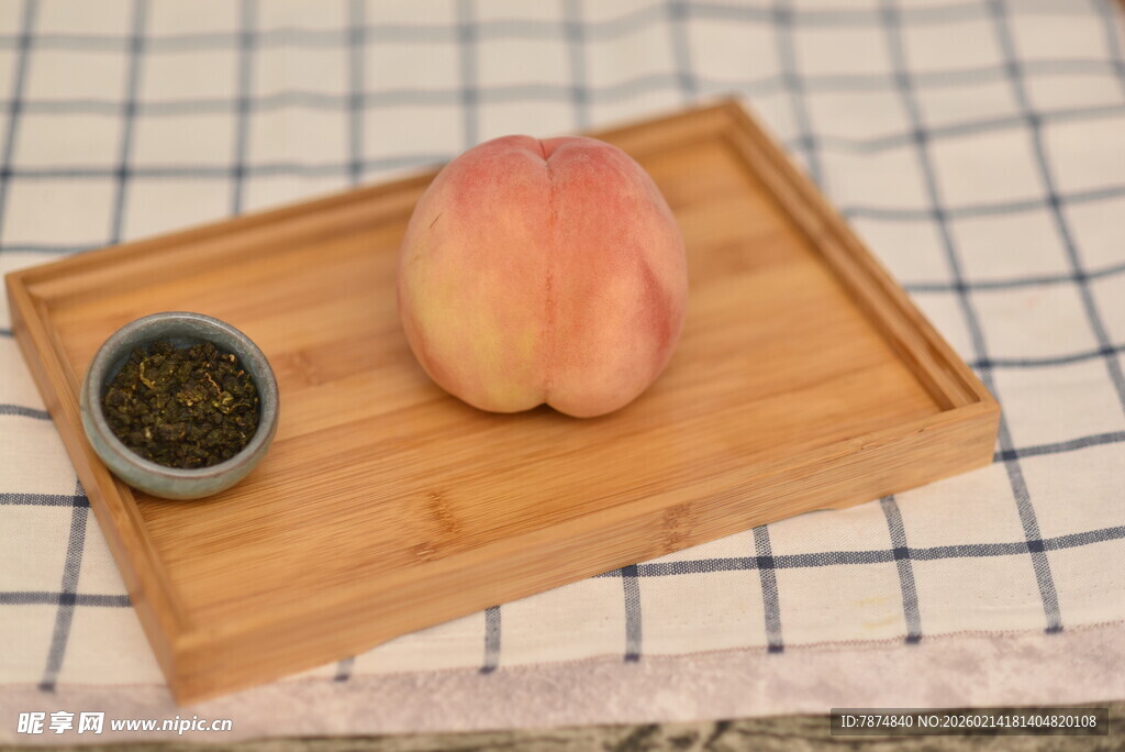 木盘上的桃子与一小碟茶叶