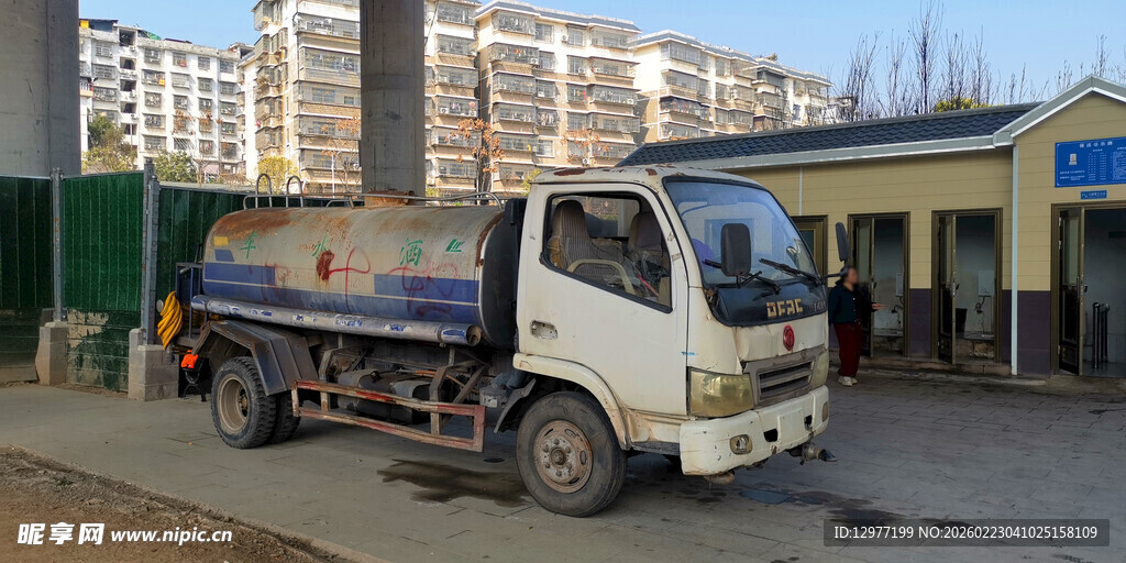 白色吸污车停于公厕建筑物旁