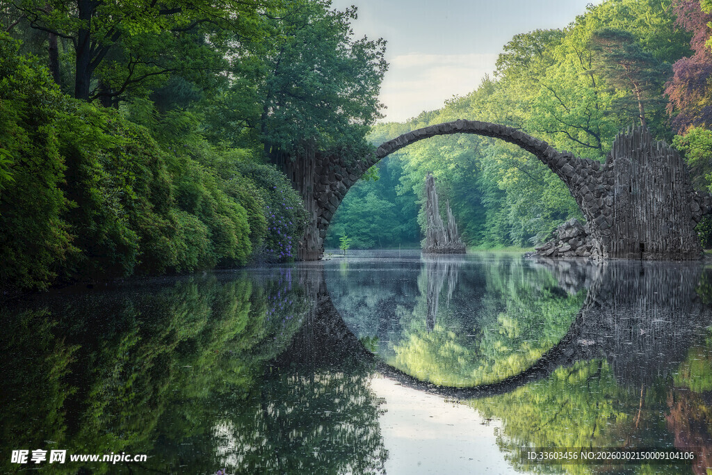 森林中拱形石桥的静谧倒影