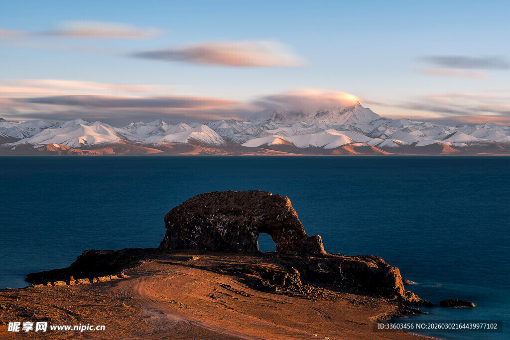 海边孤岩与远处雪山美景