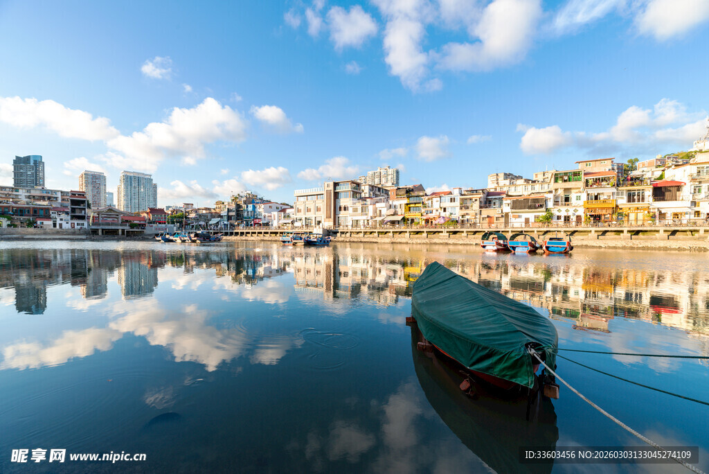 宁静港湾中的小船与城市倒影