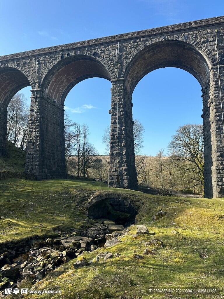 古老石拱桥横跨草地溪流