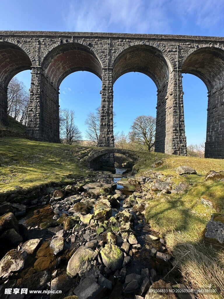 古老石拱桥横跨草地溪流