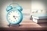 蓝色闹钟置于书本旁