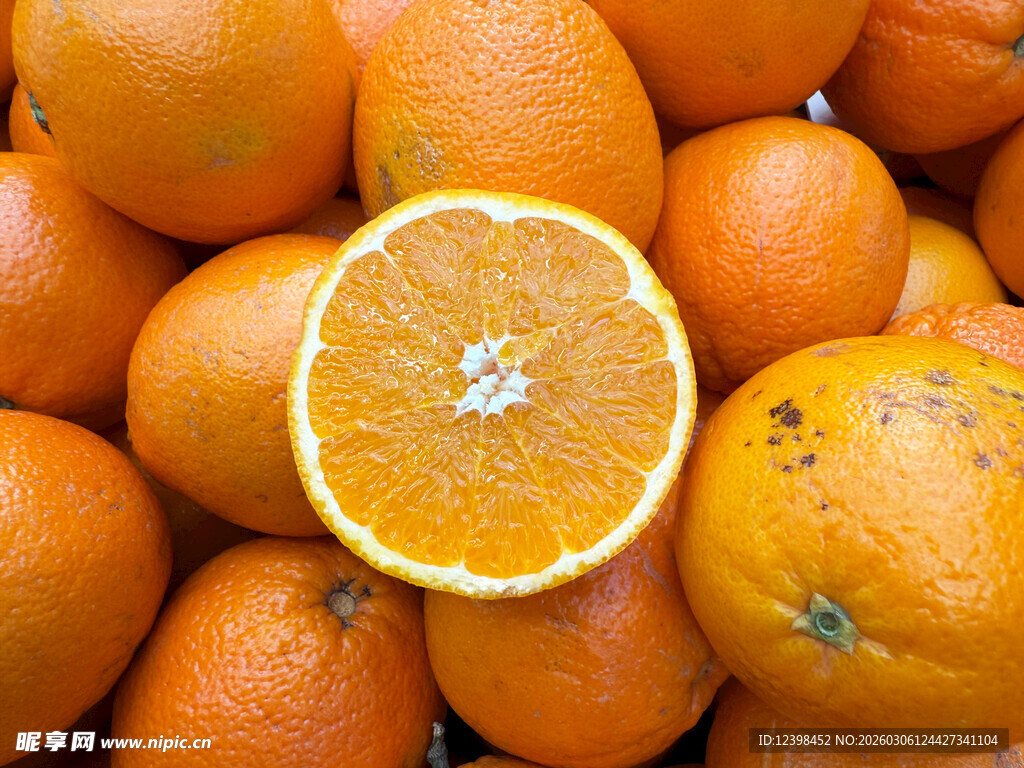 一堆鲜橙中的半颗切开橙