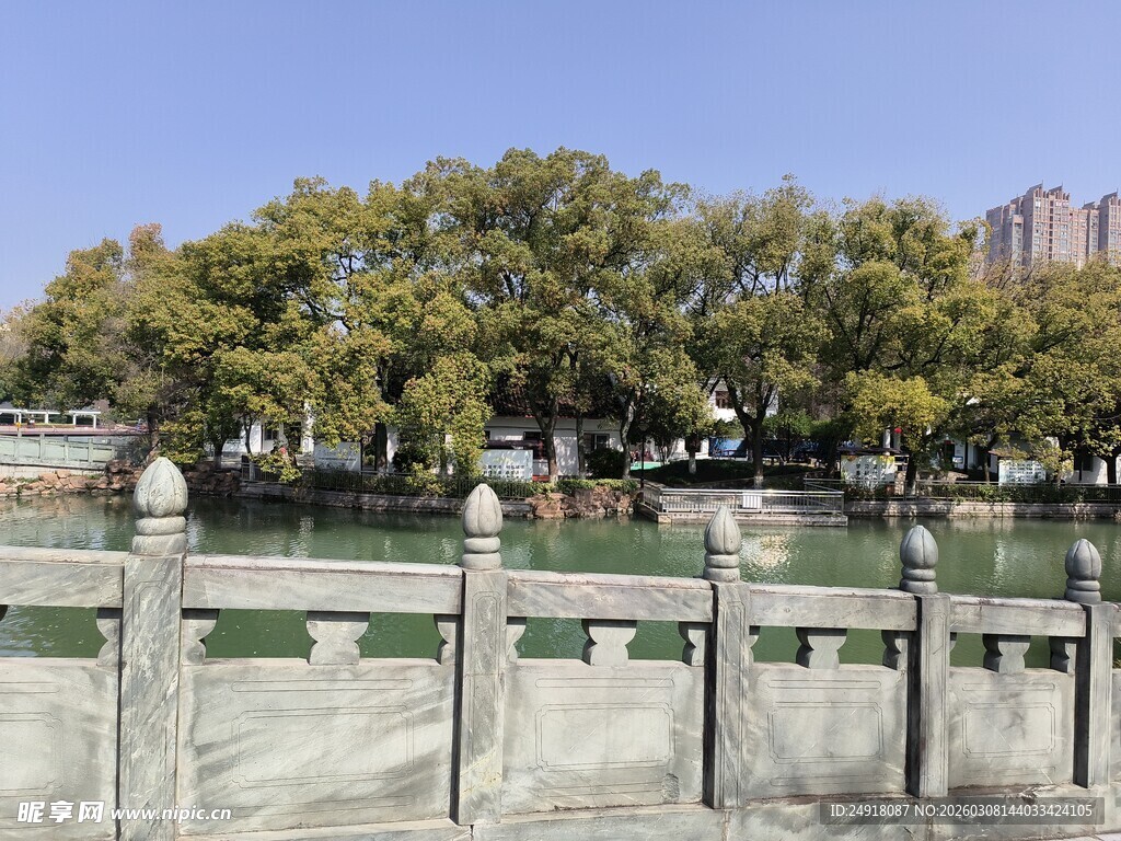 湖畔石栏旁葱郁树木景观