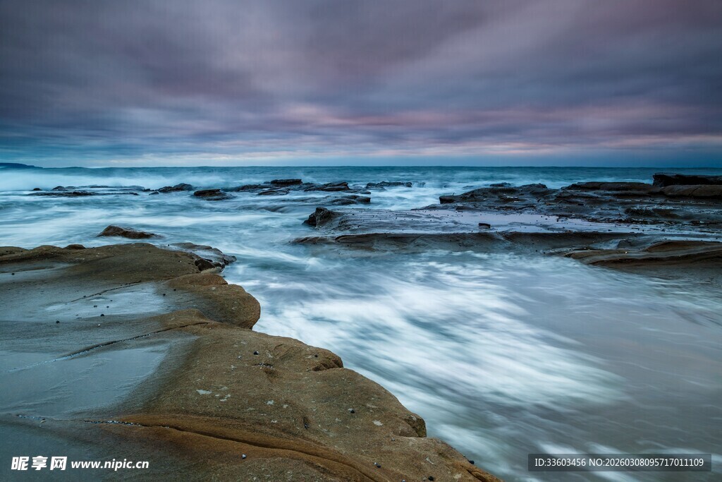 海边暮色下的礁石与海浪