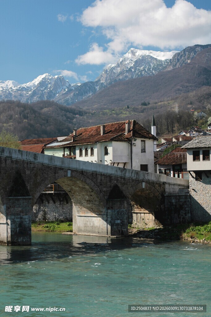河畔石桥与远处雪山美景