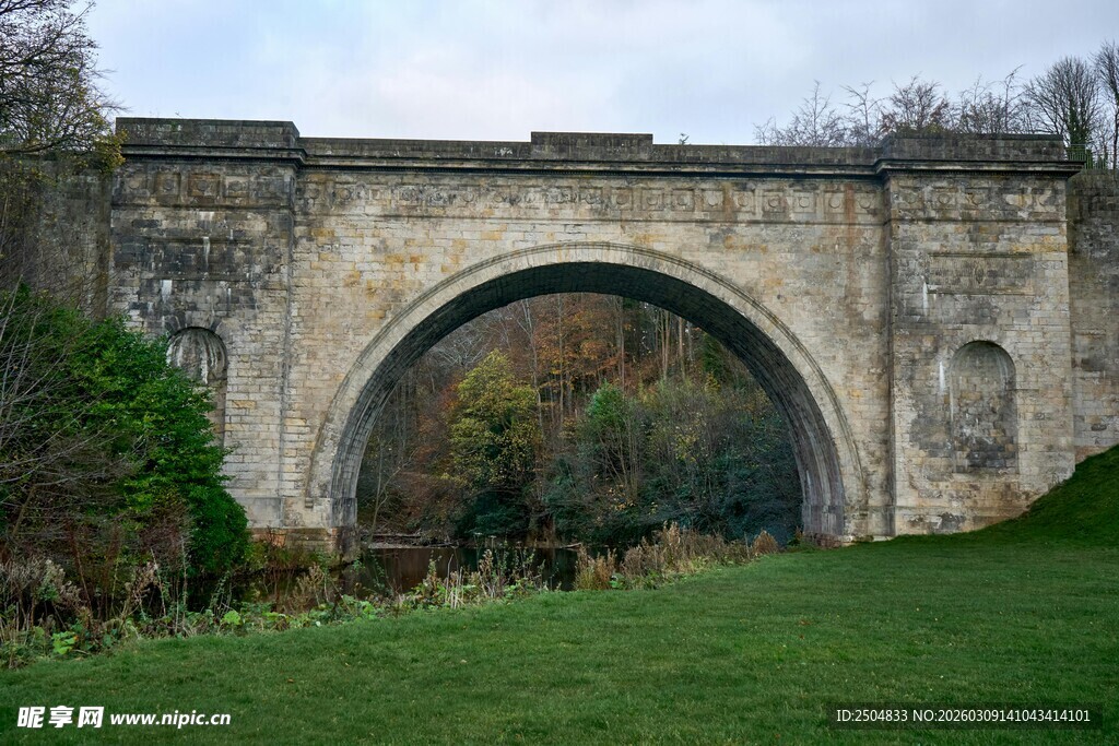 古老石拱桥横跨绿茵草地