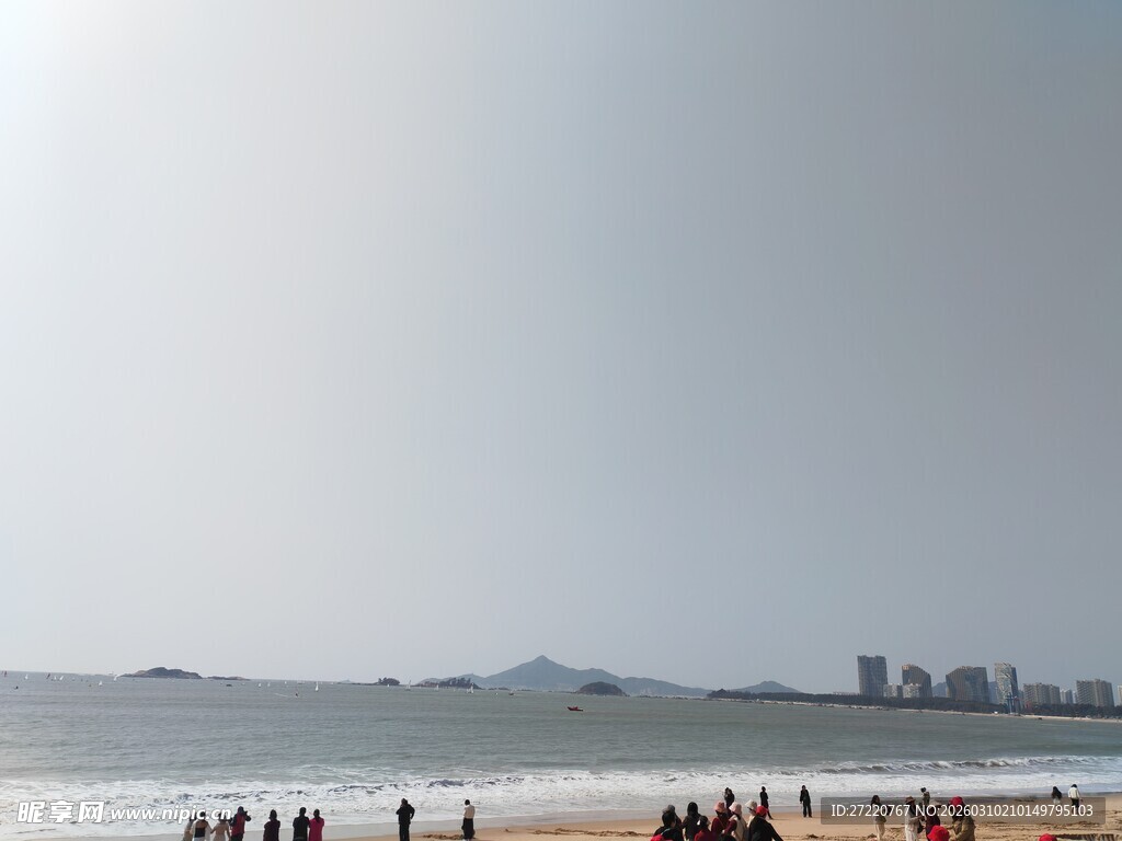 海滩上的人群与远处城市