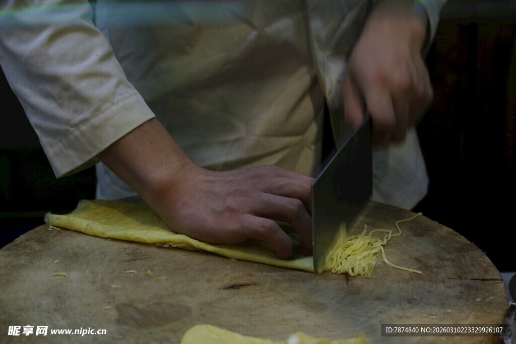 厨师持刀切菜于案板上