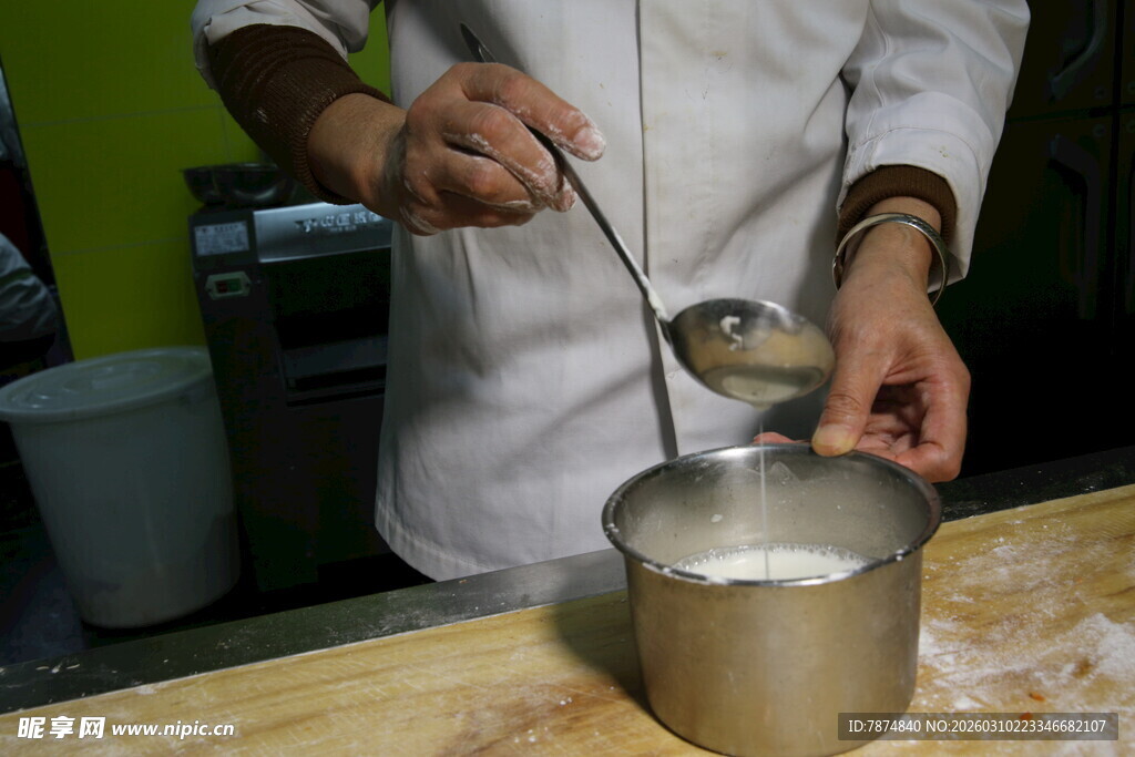 厨师正在用勺操作金属锅