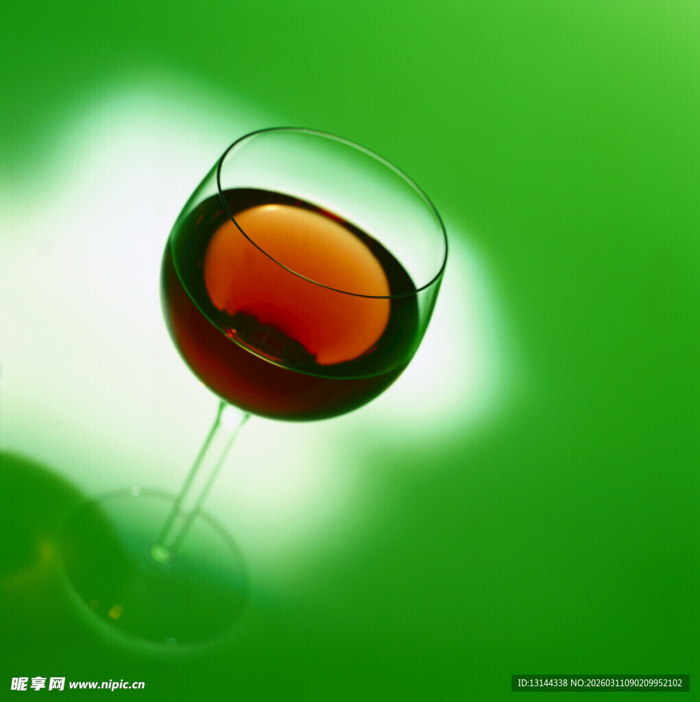 绿背景中的红酒高脚杯