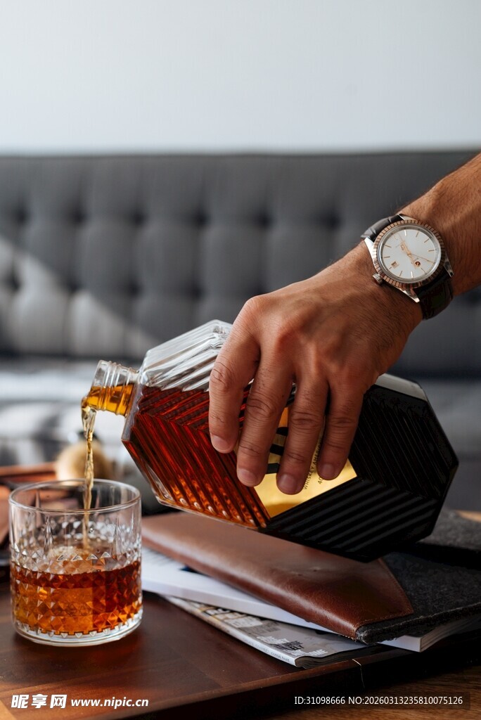 手倒威士忌于玻璃杯