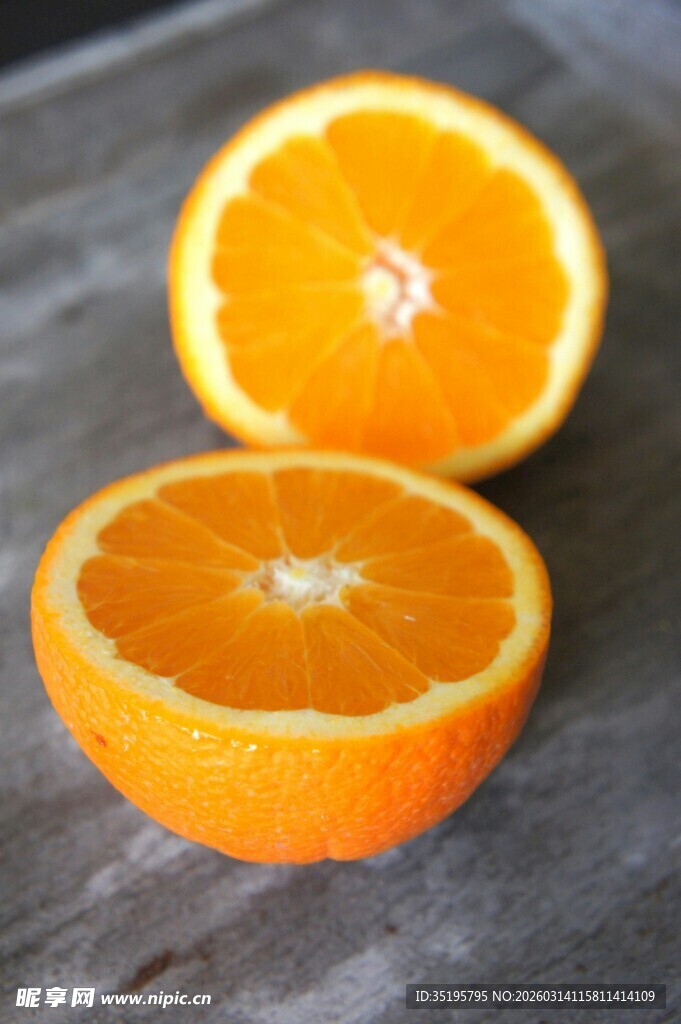 两半鲜橙置于木桌上