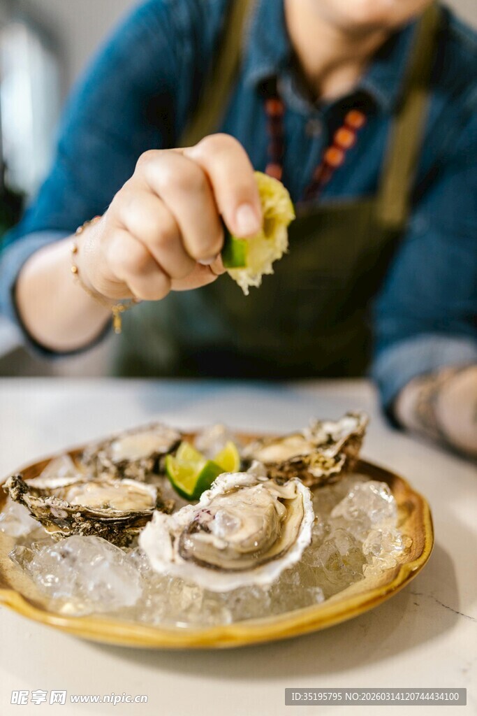手挤柠檬于冰盘生蚝上