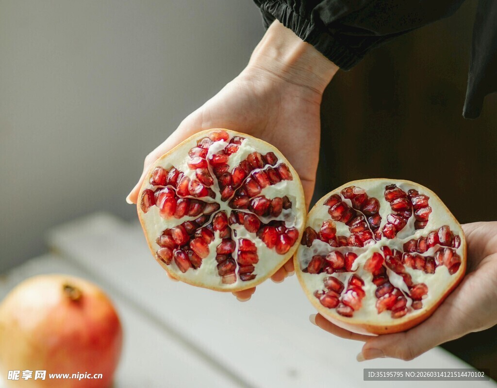 双手捧持切开的新鲜石榴
