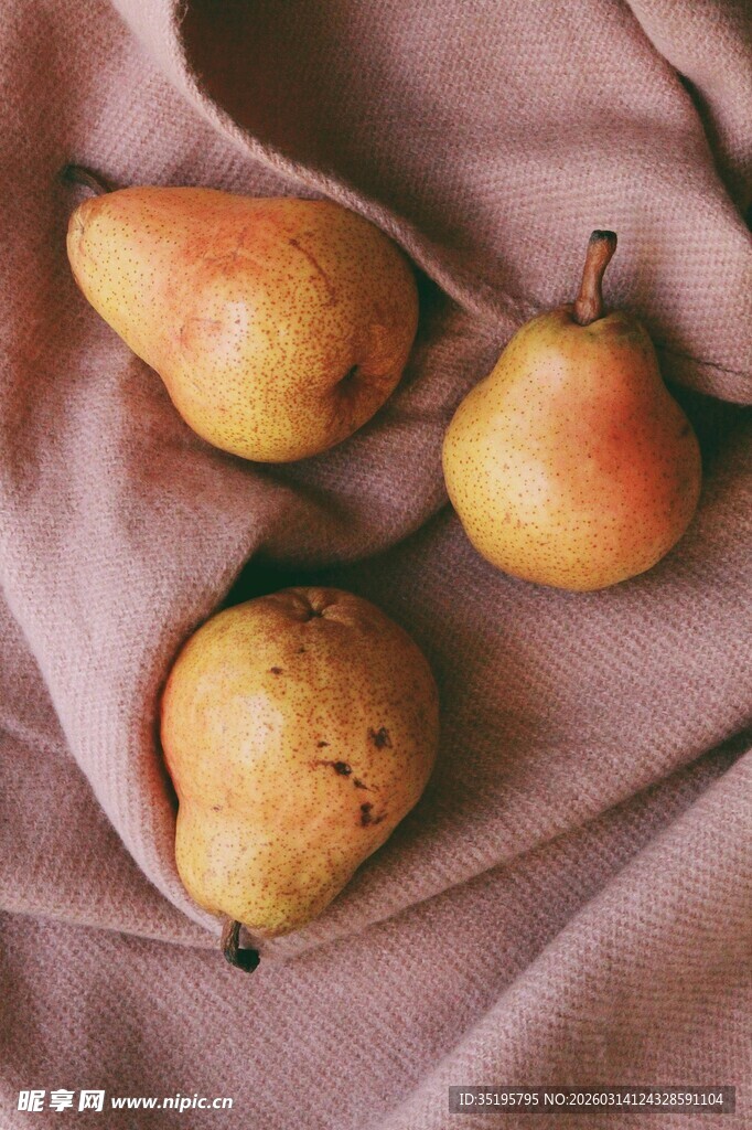 布上摆放的三颗新鲜梨子