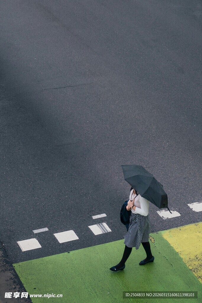 雨中行人撑伞走过斑马线