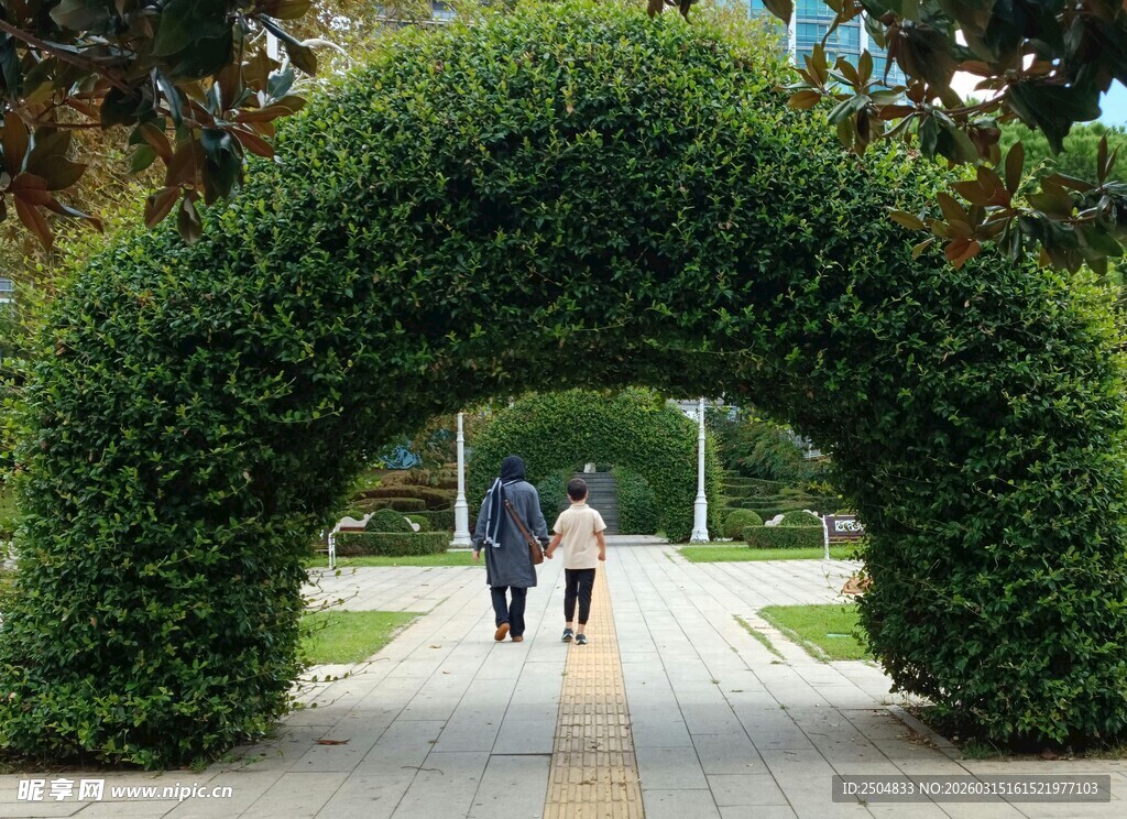 绿植拱门小道上的行人