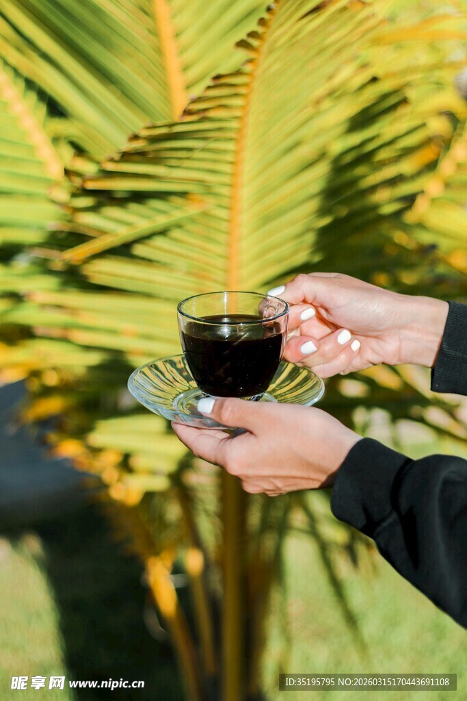 手持咖啡于绿植前的惬意