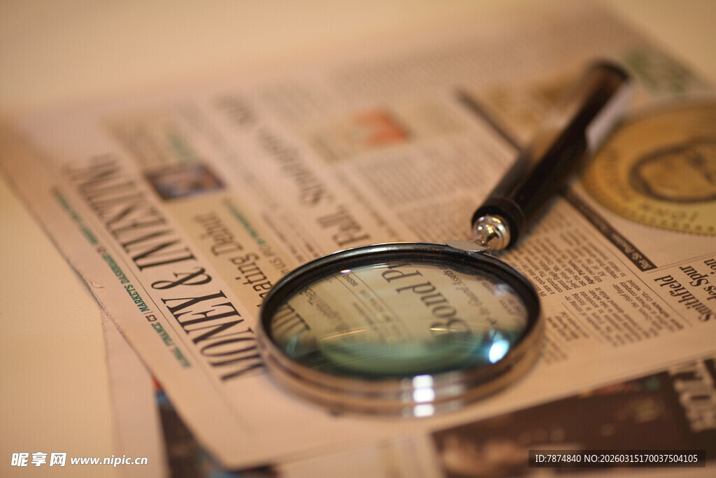 放大镜下的报纸与钢笔