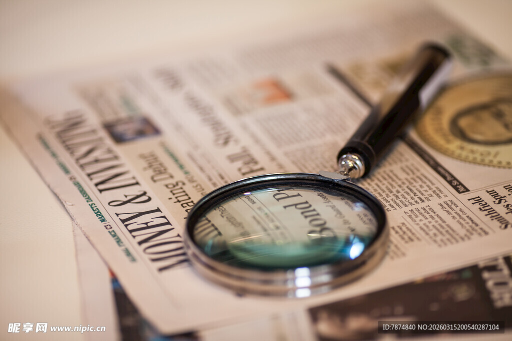 放大镜下的报纸与钢笔
