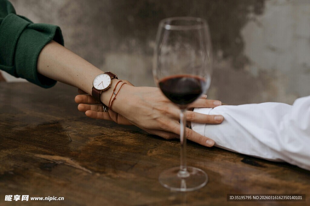 情侣桌前牵手共品红酒