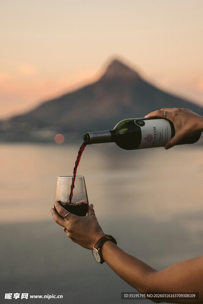 夕阳下举杯倒红酒的人