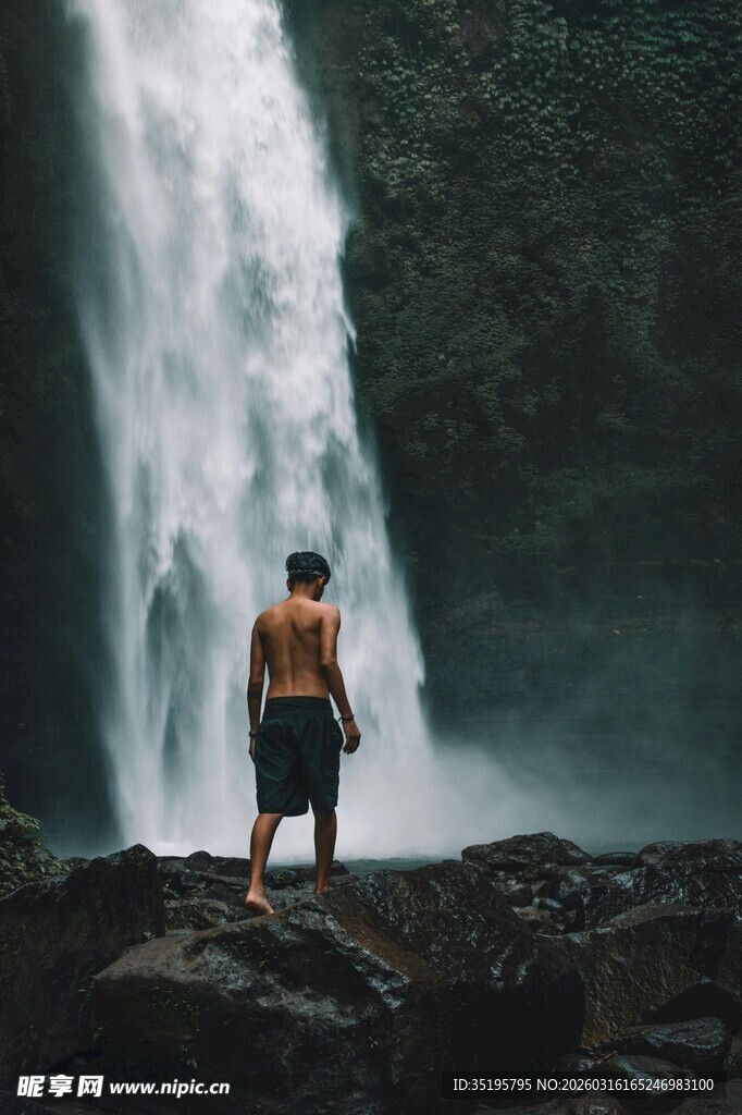 男子独立于瀑布前的身影