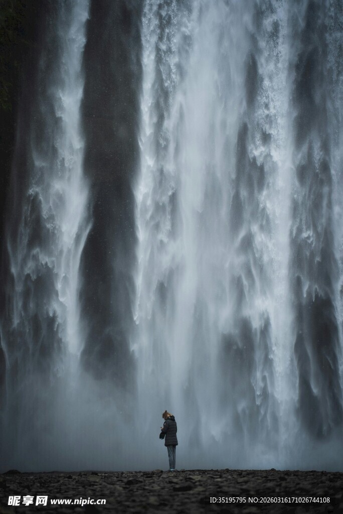 人立于磅礴瀑布前的景象