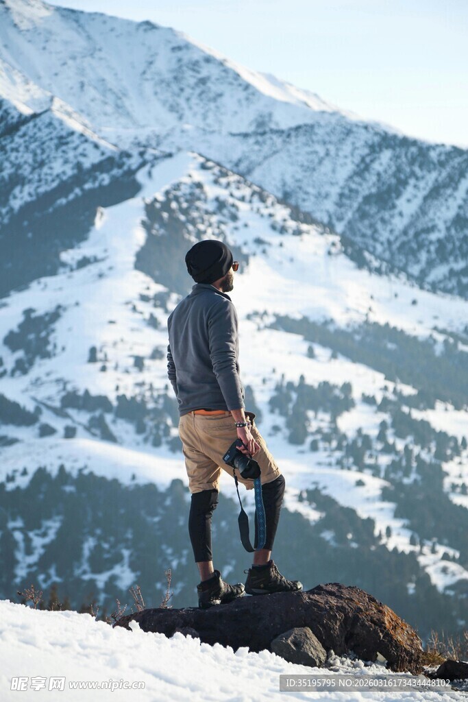 男子立于雪山前眺望远方