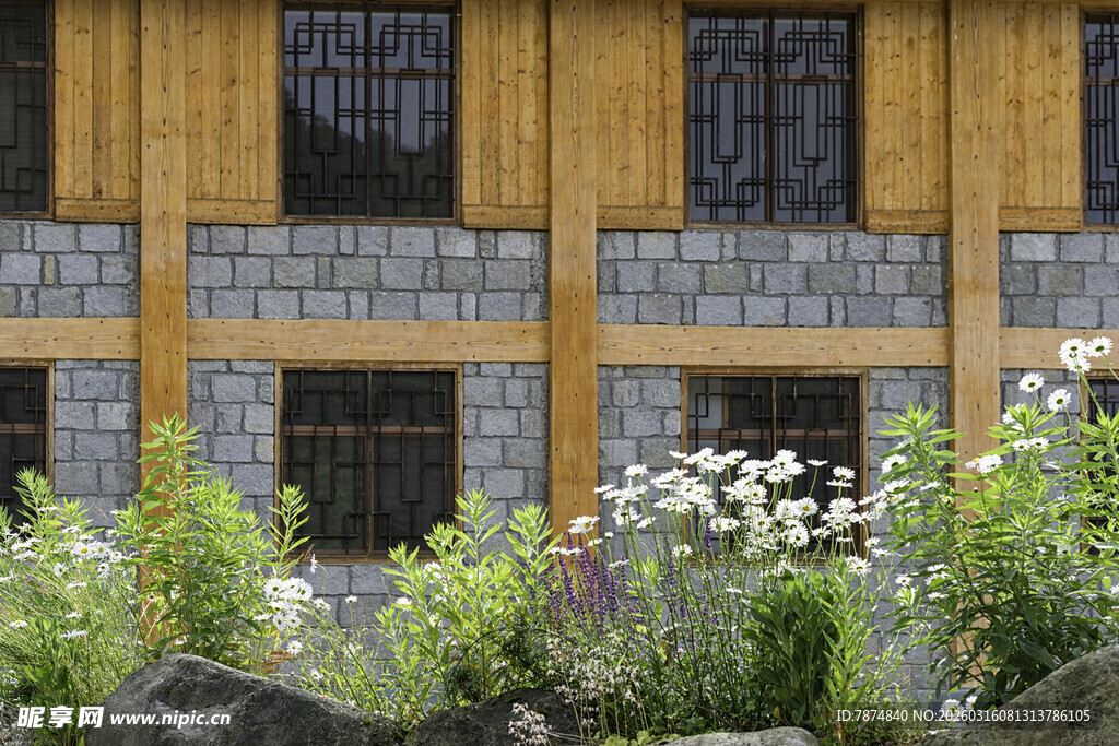 木质石砌房屋前的花草景