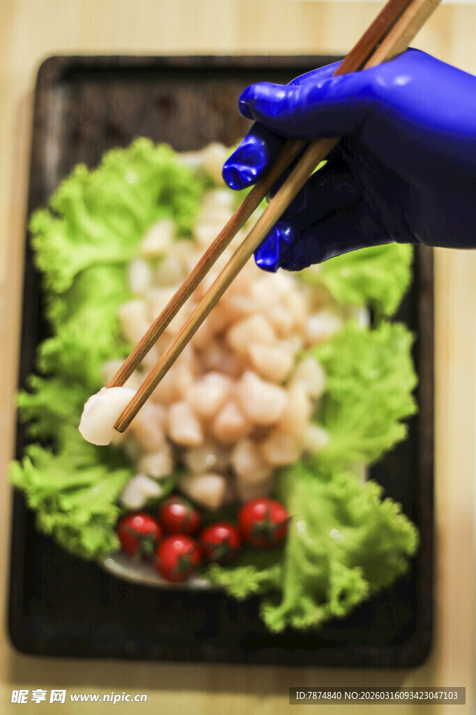 蓝手套持筷夹取盘中虾仁