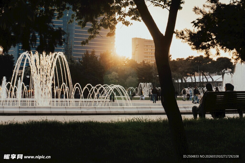 夕阳下的喷泉与休憩身影