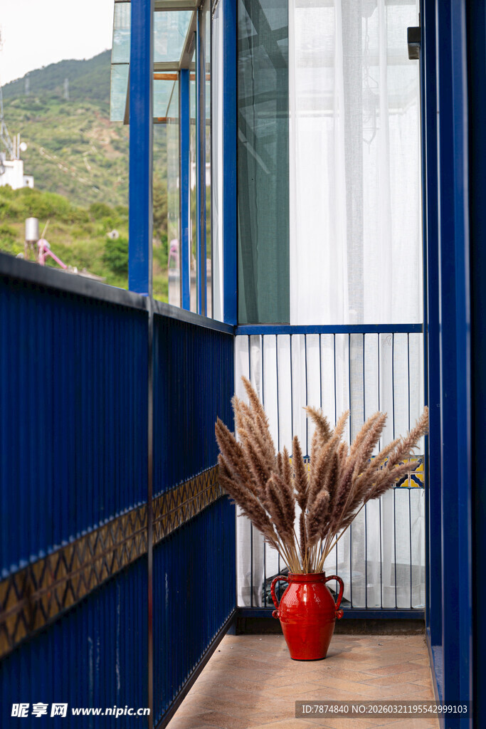 蓝色阳台的红色花瓶景致