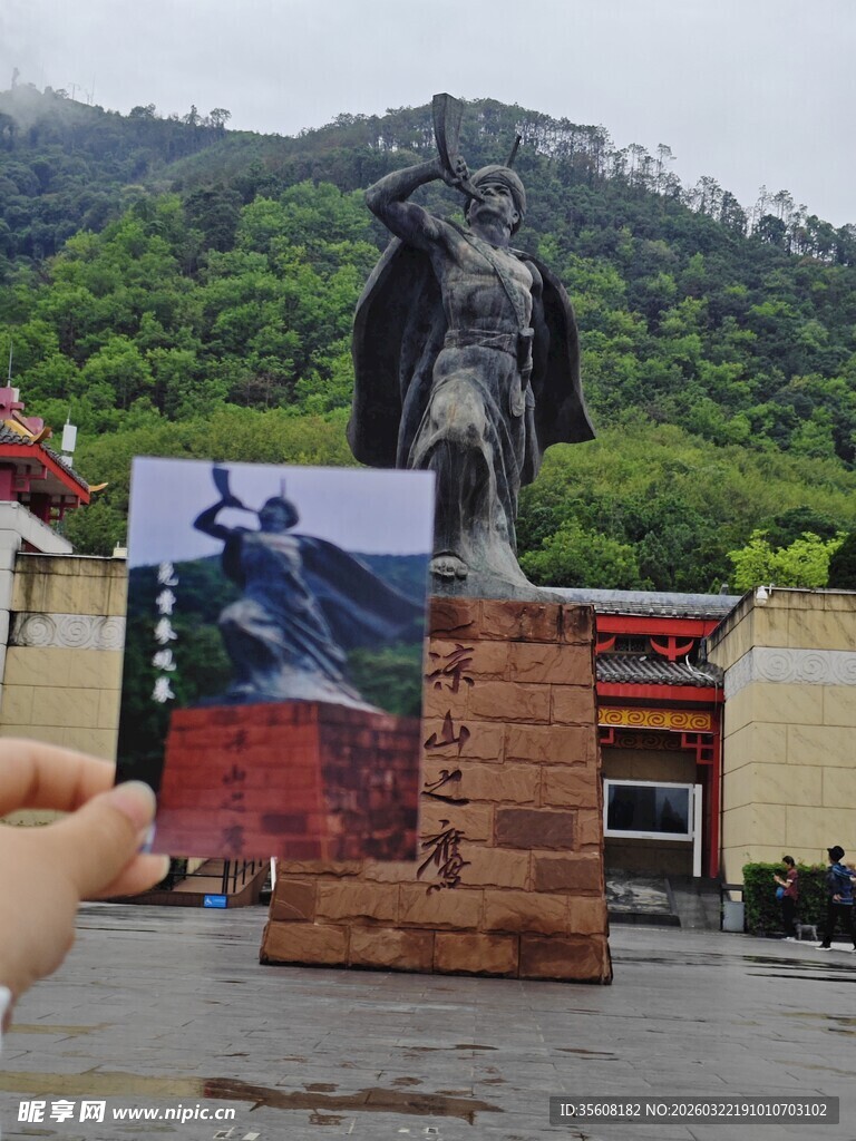 手持照片与雕像合影瞬间