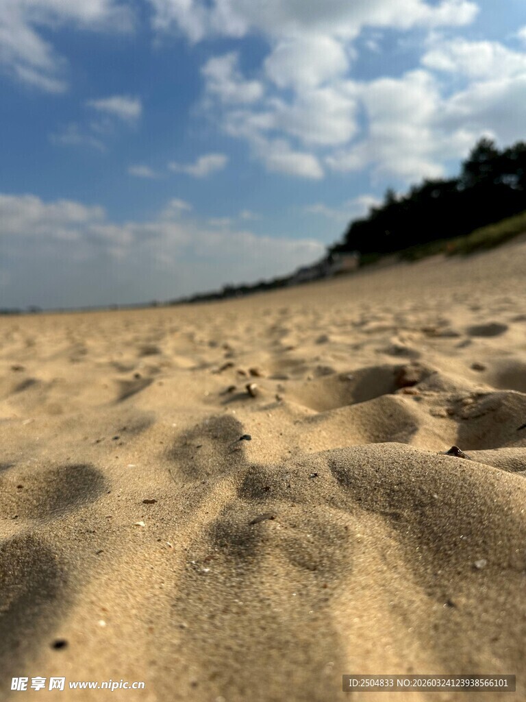 金黄沙滩与远处蓝天绿树