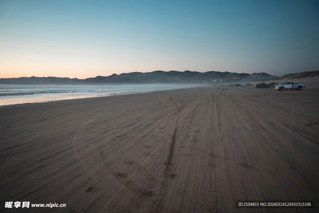 黄昏下的静谧沙滩与车辆