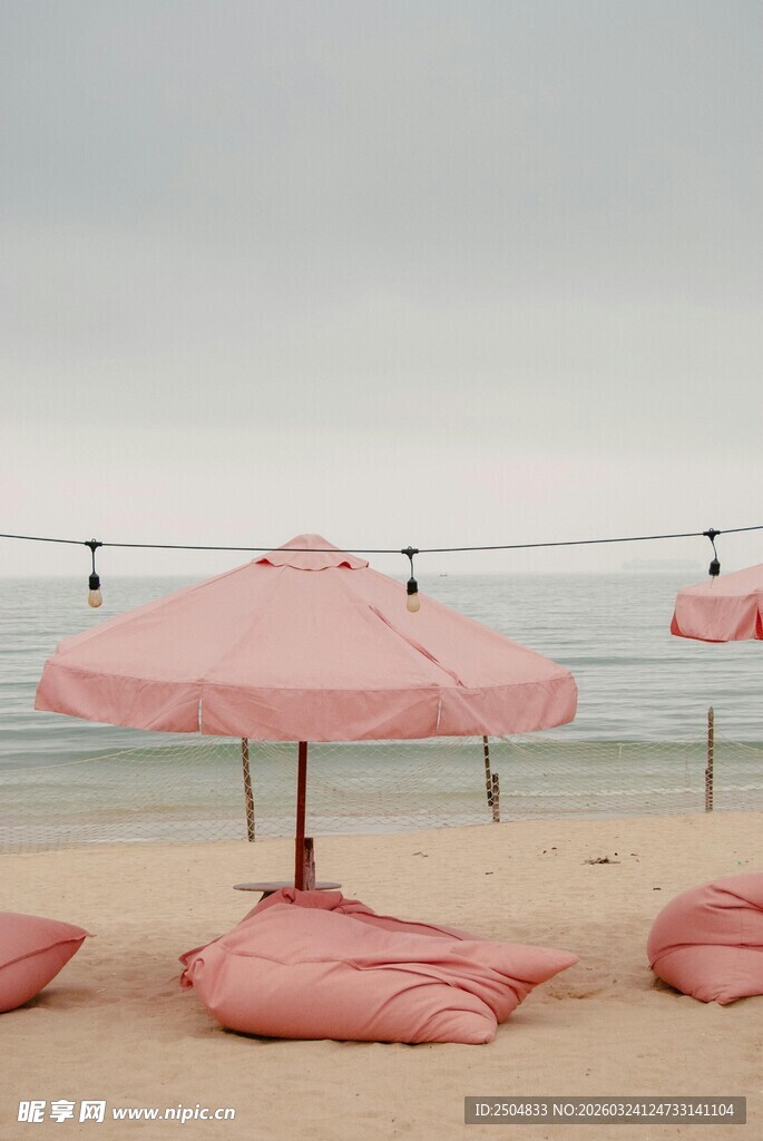 沙滩上的粉色遮阳伞与躺椅