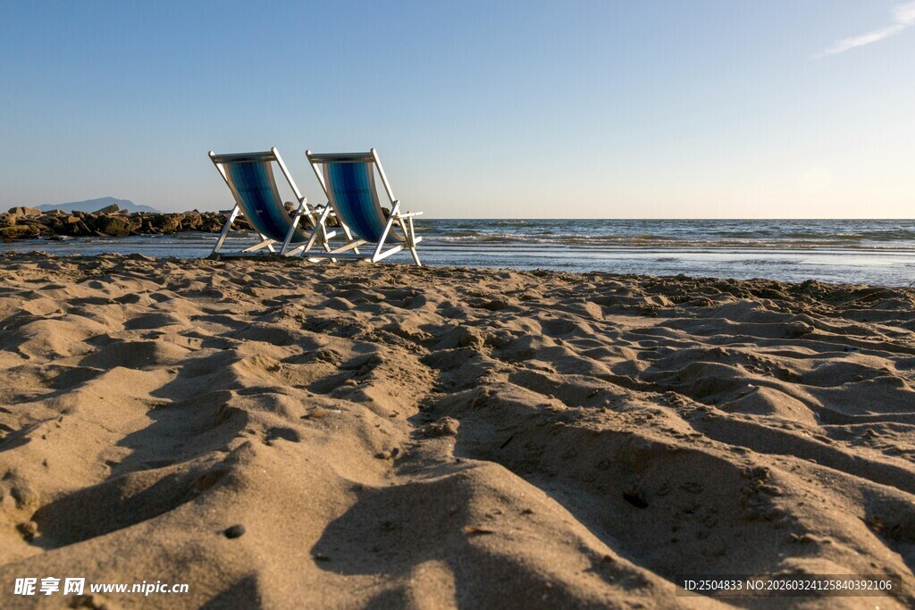 沙滩上的两把休闲躺椅