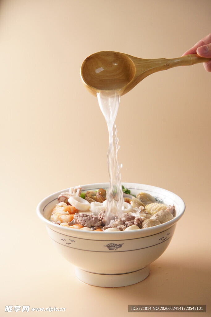木勺舀液体倒入食材丰富的碗